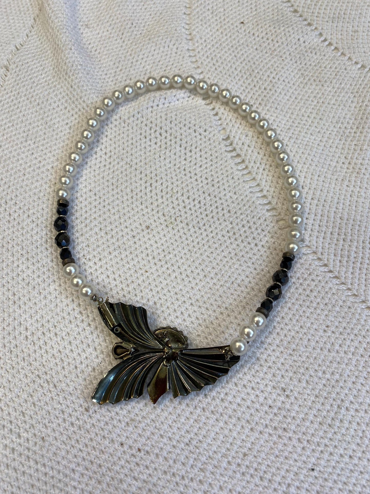 Collana sintetica perline bianche nere con ciondolo ali dorate e perla centrale, diametro 13 cm, gioiello fatto a mano elegante